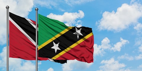 Trinidad And Tobago and Saint Kitts And Nevis flag waving in the wind against white cloudy blue sky...
