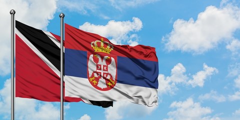 Trinidad And Tobago and Serbia flag waving in the wind against white cloudy blue sky together. Diplomacy concept, international relations.