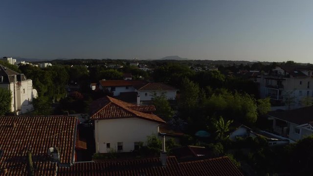 Aerial Drone Shot over french houses with orange tiled roofs in Basque country, France. French city in 4K UHD, the day. Mountains background in blue sky.