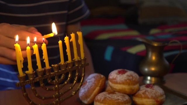 Chanukiah or Chanukah Menorah (Temple). A man sets up the candles for Jewish Holiday Hanukkah and recites the candle blessings. Hanukkah Jelly Doughnuts (Sufganiyot)