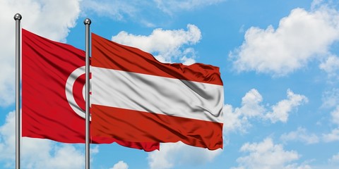Tunisia and Austria flag waving in the wind against white cloudy blue sky together. Diplomacy concept, international relations.