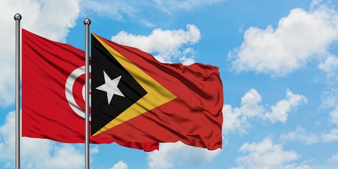 Tunisia and East Timor flag waving in the wind against white cloudy blue sky together. Diplomacy concept, international relations.