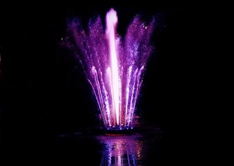 Night light purple fountain splash with reflection on water. Rusanivka island, Kyiv, Ukraine