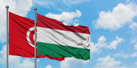 Tunisia and Hungary flag waving in the wind against white cloudy blue sky together. Diplomacy concept, international relations.