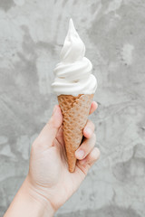 Vanilla soft serve ice cream cone in hand