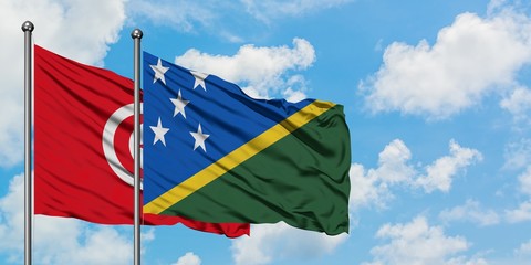 Tunisia and Solomon Islands flag waving in the wind against white cloudy blue sky together. Diplomacy concept, international relations.