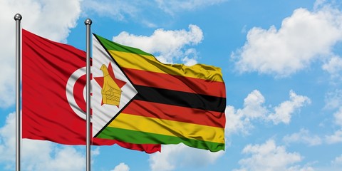 Tunisia and Zimbabwe flag waving in the wind against white cloudy blue sky together. Diplomacy concept, international relations.