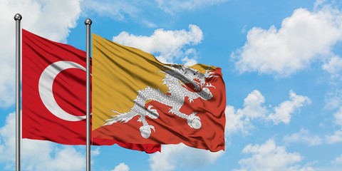 Turkey and Bhutan flag waving in the wind against white cloudy blue sky together. Diplomacy concept, international relations.