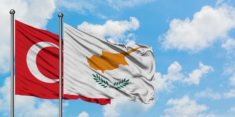 Turkey and Cyprus flag waving in the wind against white cloudy blue sky together. Diplomacy...