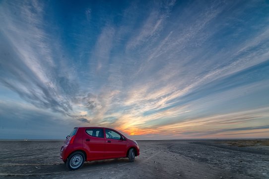 Red Car Parked At The Beach During A Sunset