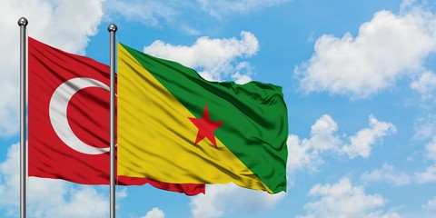 Turkey and French Guiana flag waving in the wind against white cloudy blue sky together. Diplomacy concept, international relations.