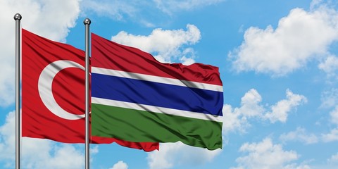 Turkey and Gambia flag waving in the wind against white cloudy blue sky together. Diplomacy...