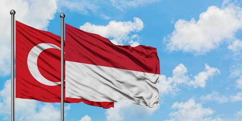 Turkey and Indonesia flag waving in the wind against white cloudy blue sky together. Diplomacy concept, international relations.