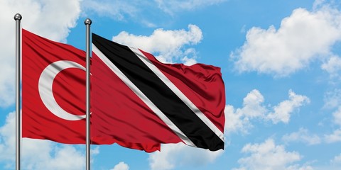 Turkey and Trinidad And Tobago flag waving in the wind against white cloudy blue sky together. Diplomacy concept, international relations.