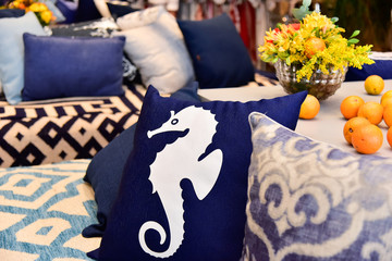blue pad with seahorse design on sofa patterned with flowers and oranges in the background , pillow shop , decoration storen, white seahorse, pillows
