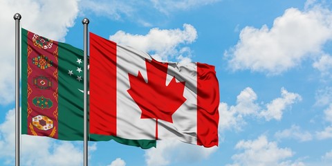 Turkmenistan and Canada flag waving in the wind against white cloudy blue sky together. Diplomacy...