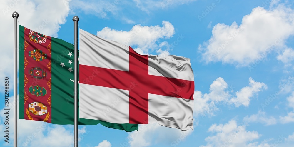 Wall mural Turkmenistan and England flag waving in the wind against white cloudy blue sky together. Diplomacy concept, international relations. - Wall murals
