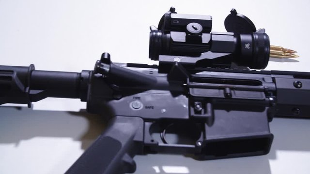 Pan of With Holographic Sight on Table From Barrel to Stock With Bullets Laying in Background