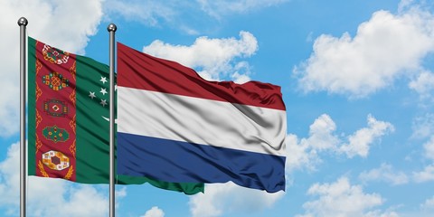 Turkmenistan and Netherlands flag waving in the wind against white cloudy blue sky together. Diplomacy concept, international relations.