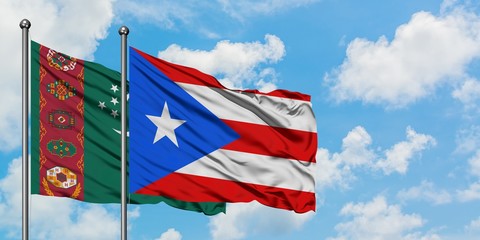 Turkmenistan and Puerto Rico flag waving in the wind against white cloudy blue sky together. Diplomacy concept, international relations.