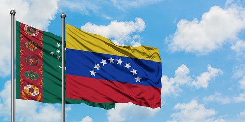 Turkmenistan and Venezuela flag waving in the wind against white cloudy blue sky together. Diplomacy concept, international relations.