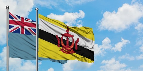 Tuvalu and Brunei flag waving in the wind against white cloudy blue sky together. Diplomacy concept, international relations.