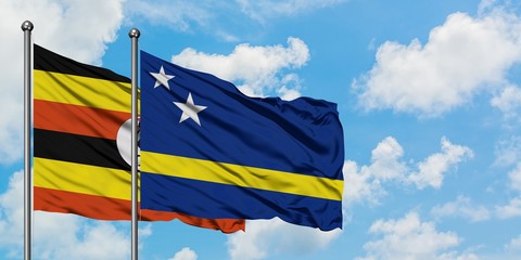 Uganda and Curacao flag waving in the wind against white cloudy blue sky together. Diplomacy concept, international relations.
