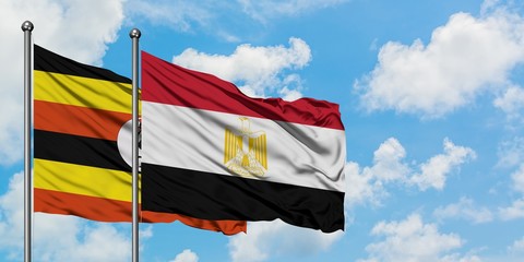 Uganda and Egypt flag waving in the wind against white cloudy blue sky together. Diplomacy concept, international relations.