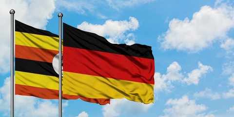 Uganda and Germany flag waving in the wind against white cloudy blue sky together. Diplomacy concept, international relations.
