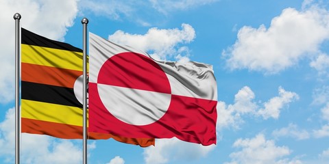 Uganda and Greenland flag waving in the wind against white cloudy blue sky together. Diplomacy...