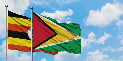 Uganda and Guyana flag waving in the wind against white cloudy blue sky together. Diplomacy concept, international relations.