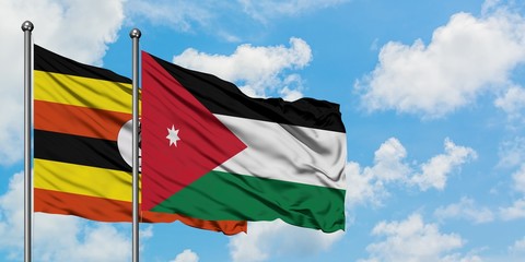 Uganda and Jordan flag waving in the wind against white cloudy blue sky together. Diplomacy concept, international relations.