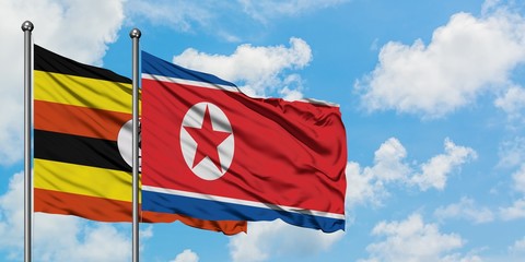Uganda and North Korea flag waving in the wind against white cloudy blue sky together. Diplomacy concept, international relations.