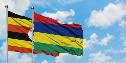 Uganda and Mauritius flag waving in the wind against white cloudy blue sky together. Diplomacy concept, international relations.