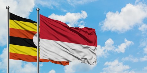 Uganda and Monaco flag waving in the wind against white cloudy blue sky together. Diplomacy concept, international relations.