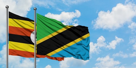 Uganda and Tanzania flag waving in the wind against white cloudy blue sky together. Diplomacy concept, international relations.