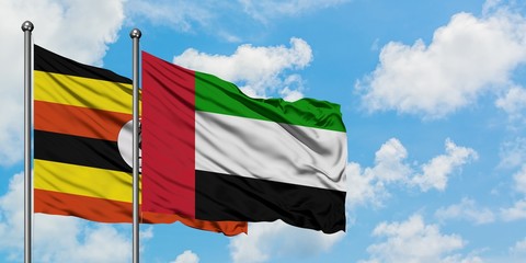 Uganda and United Arab Emirates flag waving in the wind against white cloudy blue sky together. Diplomacy concept, international relations.