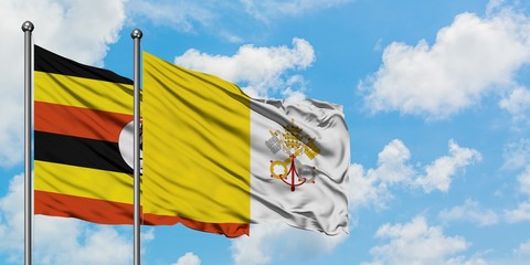 Uganda and Vatican City flag waving in the wind against white cloudy blue sky together. Diplomacy...