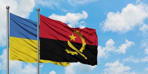 Ukraine and Angola flag waving in the wind against white cloudy blue sky together. Diplomacy...