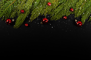 Christmas composition. Girlanda with red Christmas baubles and snow on black background. Christmas, winter, new year concept. Flat lay, top view, copy space. © Julio Ricco