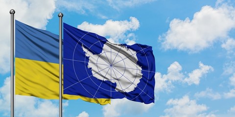 Ukraine and Antarctica flag waving in the wind against white cloudy blue sky together. Diplomacy concept, international relations.