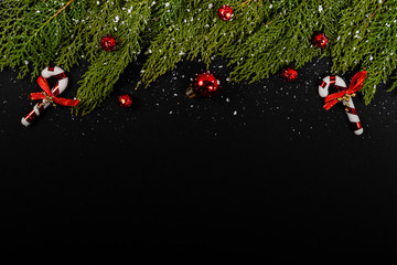 Christmas composition. Girlanda with red Christmas baubles and snow on black background. Christmas, winter, new year concept. Flat lay, top view, copy space. © Julio Ricco
