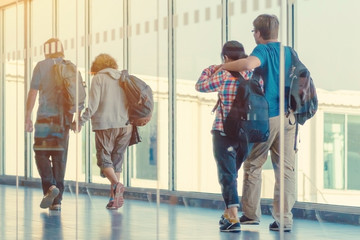 Back view of passengers and traveling luggage walking the airplane boarding corridor from the terminal to the plane.