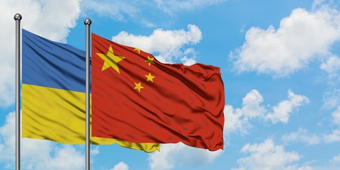 Ukraine and China flag waving in the wind against white cloudy blue sky together. Diplomacy concept, international relations.