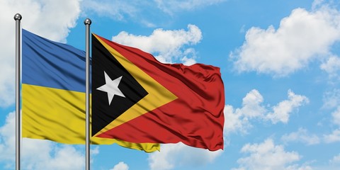 Ukraine and East Timor flag waving in the wind against white cloudy blue sky together. Diplomacy concept, international relations.