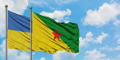 Ukraine and French Guiana flag waving in the wind against white cloudy blue sky together. Diplomacy concept, international relations.