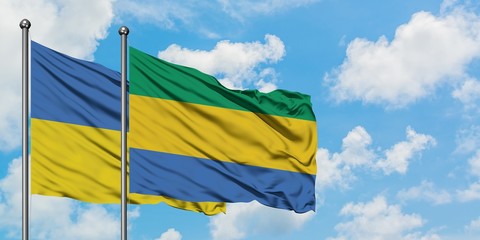 Ukraine and Gabon flag waving in the wind against white cloudy blue sky together. Diplomacy...