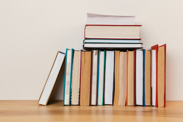 Simple composition of many hardback books, raw of books on wooden table and light  background