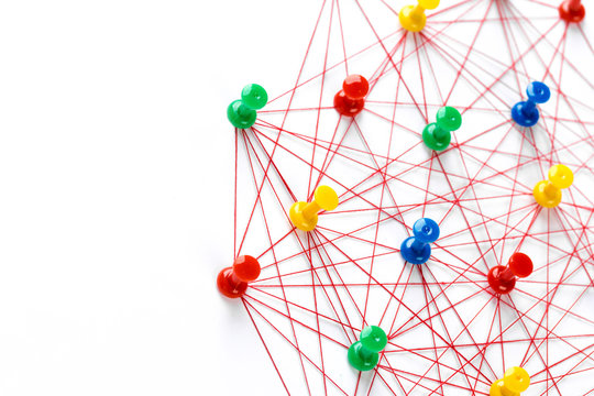 Network with colorful pins and string,  linked together with string on a white background suggesting a network of connections.