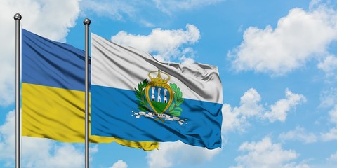 Ukraine and San Marino flag waving in the wind against white cloudy blue sky together. Diplomacy concept, international relations.